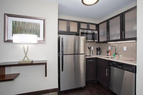 a kitchen with a stainless steel refrigerator and black cabinets at Staybridge Suites Denver South - Highlands Ranch by IHG in Littleton