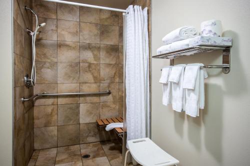 y baño con ducha, aseo y toallas. en Candlewood Suites Olympia - Lacey, an IHG Hotel en Lacey