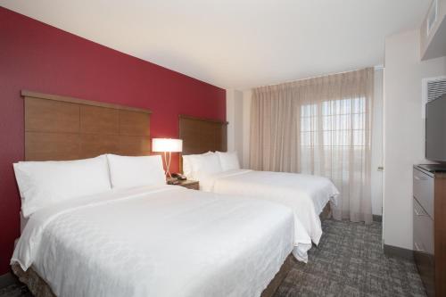 two beds in a hotel room with red walls at Staybridge Suites Denver International Airport by IHG in Denver