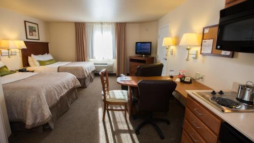 Candlewood Suites Joplin, an IHG Hotel في جوبلين: غرفة فندقية بسريرين ومكتب