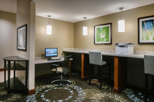 Staybridge Suites Des Moines Downtown, an IHG Hotel في دي موين: يوجد بار به كمبيوتر ومكتب به كراسي