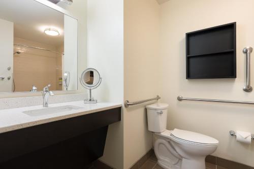 a bathroom with a toilet and a sink and a mirror at Candlewood Suites Lenexa - Overland Park Area by IHG in Lenexa