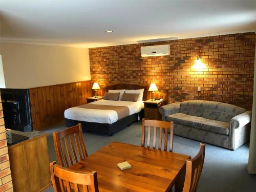 a hotel room with a bed and a couch and a table at Victoriana Motor Inn in Ballarat