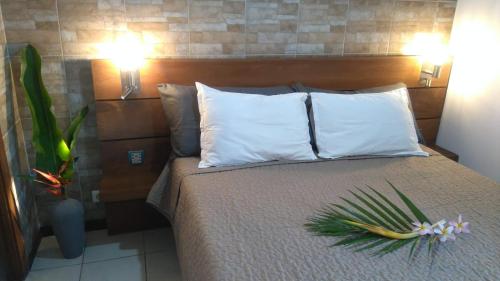 a bedroom with a bed with pillows and a plant on it at Orio Papeete centre apt w pool in Papeete