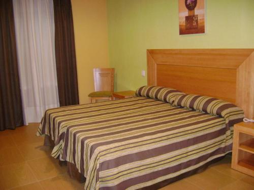 um quarto com uma cama com um cobertor listrado em Hostal Jijones em Villarrubia de los Ojos
