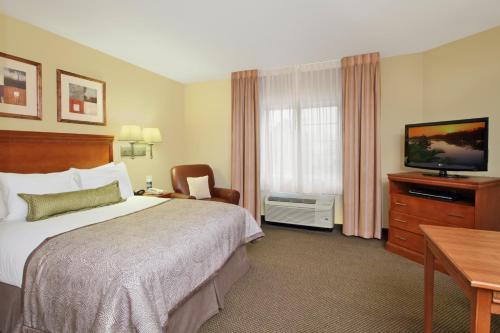 a hotel room with a bed and a flat screen tv at Candlewood Suites Norfolk Airport by IHG in Norfolk