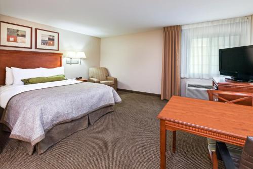a hotel room with a bed and a flat screen tv at Candlewood Suites Owasso by IHG in Owasso