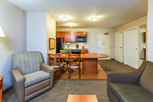 a living room with a couch and a table and a kitchen at Candlewood Suites Owasso by IHG in Owasso