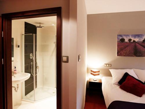 a bedroom with a bed and a shower and a sink at Hotel Otoliński in Płock