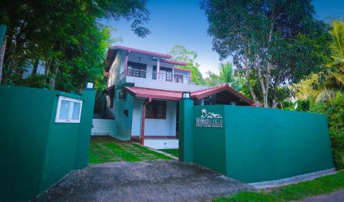 a house with a green fence in front of it at Nimnada Villa in Galle