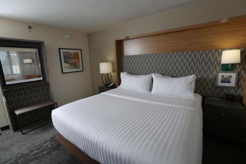 a hotel room with a large bed with white sheets at Holiday Inn Chicago North Shore by IHG in Skokie