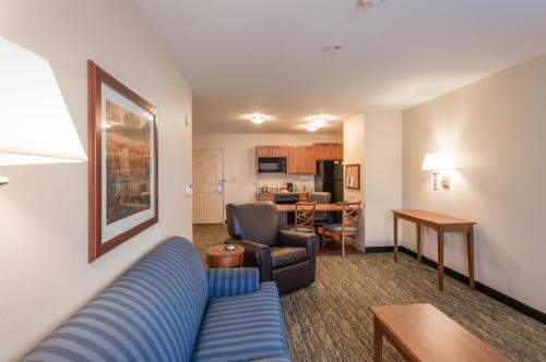 a living room with a blue couch and a kitchen at Candlewood Suites Mobile-Downtown by IHG in Mobile