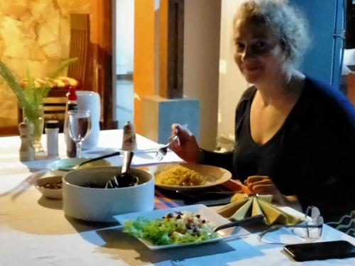 Surathura homestay في كورونيغالا: امرأة تجلس على طاولة مع طبق من الطعام
