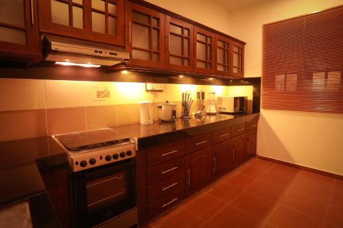 a kitchen with wooden cabinets and a stove top oven at Nimnada Villa in Galle