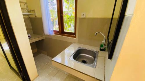 baño pequeño con lavabo y ventana en Pandawa Beach Homestay, en Uluwatu