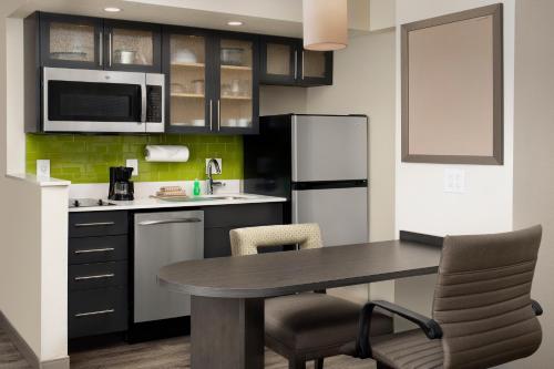 a kitchen with a table and a refrigerator at Candlewood Suites Alexandria West by IHG in Alexandria