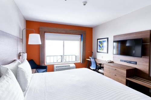 a hotel room with a bed and a flat screen tv at Holiday Inn Express Hotel & Suites Dieppe Airport by IHG in Moncton