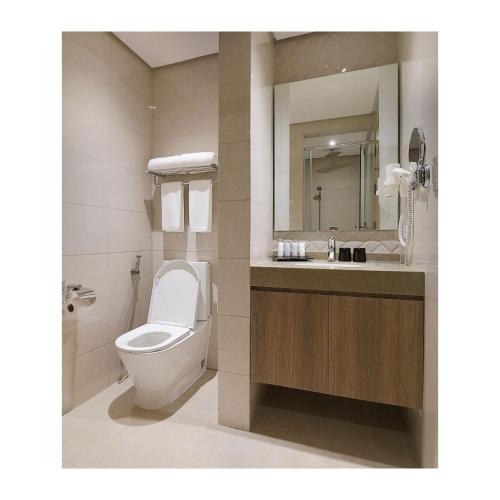 a bathroom with a toilet and a sink and a mirror at Summit Hotel Greenhills in Manila