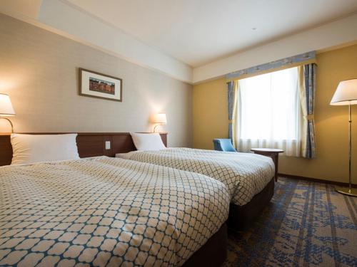 a hotel room with two beds and a window at Hotel Nikko Huis Ten Bosch in Sasebo