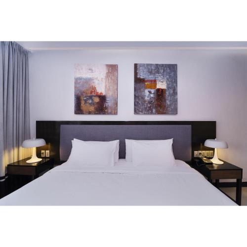a bedroom with a large white bed with two lamps at Summit Hotel Magnolia in Manila