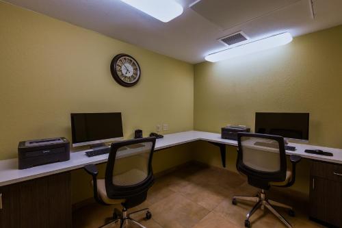 an office with two desks with two monitors and a clock at Candlewood Suites Tucson by IHG in Tucson