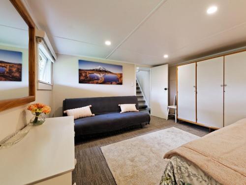 una sala de estar con un sofá y una cama en Surfer's Sunshine Cottage - Piha Holiday Home, en Piha