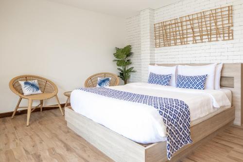a bedroom with a large bed and two chairs at VAYNA Boutique Koh Chang in Ko Chang