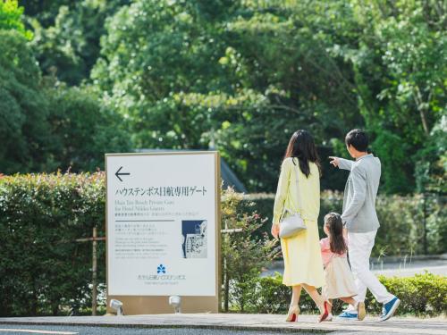 a family walking past a sign in a park at Hotel Nikko Huis Ten Bosch in Sasebo