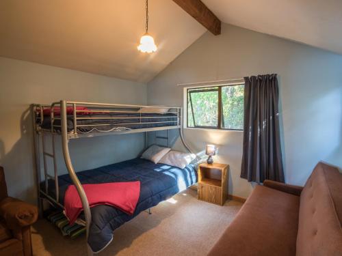 ein Schlafzimmer mit einem Etagenbett und einem Sofa in der Unterkunft Matai Cottage - Pakawau Bach in Pakawau