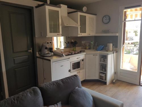 une cuisine avec des armoires blanches et un canapé dans une pièce dans l'établissement vacances à la plage, à Saint-Cyr-sur-Mer