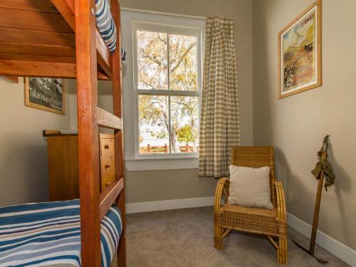 una camera con letto a castello, sedia e finestra di Kaha Cottage - Rangataua Holiday Home a Ohakune