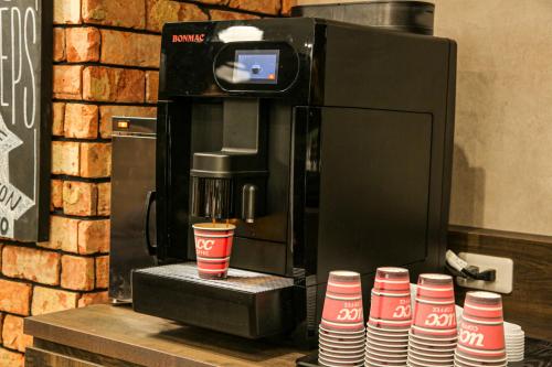 a coffee machine with a stack of red and white cups at The Celecton Matsumoto in Matsumoto