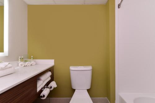 uma casa de banho com um WC branco e uma parede verde em Holiday Inn Express & Suites Raleigh NE - Medical Ctr Area, an IHG Hotel em Raleigh