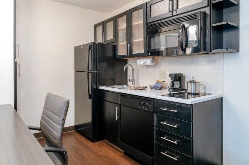 a kitchen with black cabinets and a black refrigerator at Candlewood Suites Washington-Dulles Herndon by IHG in Herndon