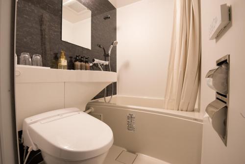 a bathroom with a white toilet and a bath tub at The Celecton Matsumoto in Matsumoto
