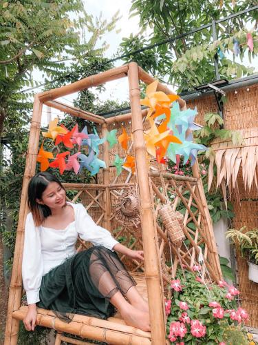 a woman sitting on a wooden frame with flowers at Green Sunshine Homestay in Can Tho