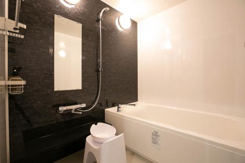 a bathroom with a tub and a toilet and a sink at The Celecton Matsumoto in Matsumoto