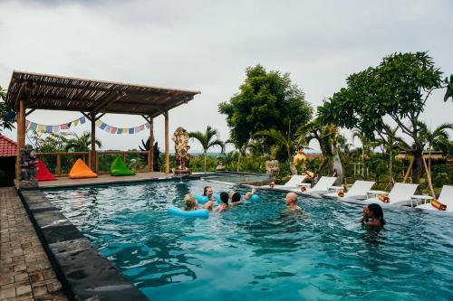 a group of people in the swimming pool at a resort at Odiyana Bali Retreat in Banyuwedang