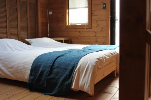 um quarto com uma cama com um cobertor azul em Alpine Chalets Hakuba em Hakuba