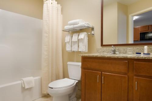Un baño con inodoro, lavabo y espejo. en Candlewood Suites Wichita Falls at Maurine Street by IHG, en Wichita Falls