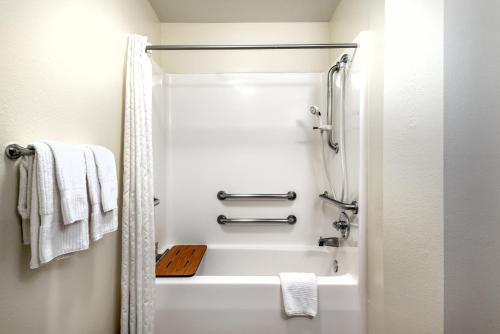 a bathroom with a shower and a white bath tub at Candlewood Suites Sterling by IHG in Sterling