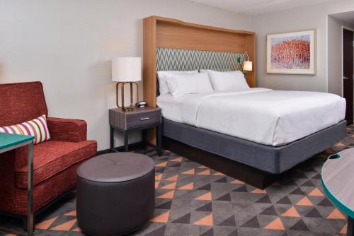 a hotel room with a bed and a chair at Holiday Inn Hotel & Suites Rochester - Marketplace by IHG in Rochester