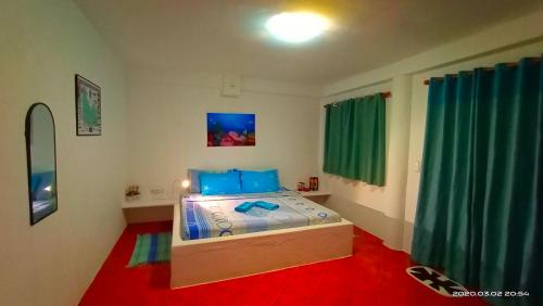 a bedroom with a bed with blue pillows and green curtains at Aquarius Terraces Boutique Resort in Boracay