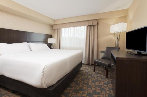 a hotel room with a bed and a desk and a television at Holiday Inn Express Hotel & Suites Uptown Fredericton by IHG in Fredericton