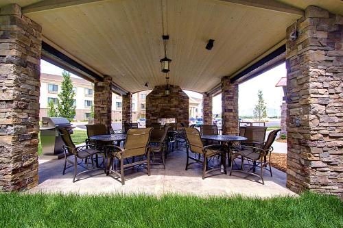 a covered patio with tables and chairs on it at Staybridge Suites Salt Lake-West Valley City by IHG in West Valley City