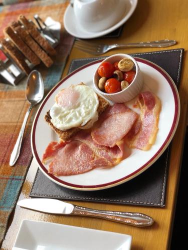 a plate of breakfast food with eggs and bacon at Carisbrooke Guest House in Inverness