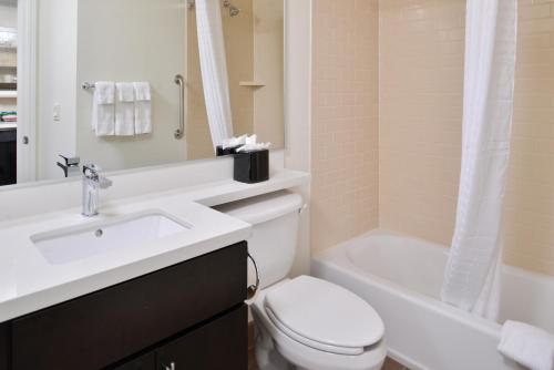 a bathroom with a sink and a toilet and a tub at Candlewood Suites Beaumont by IHG in Beaumont