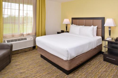 a hotel room with a large bed and a couch at Candlewood Suites Beaumont by IHG in Beaumont