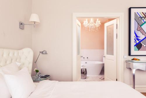a white bedroom with a bed and a bath tub at Hotel Sans Souci Wien in Vienna