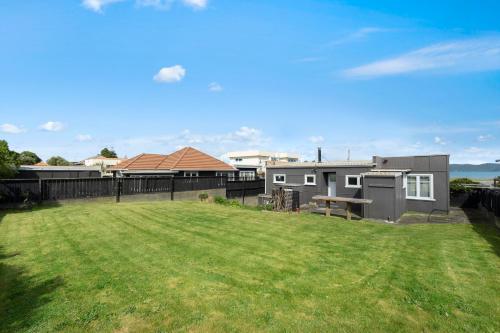 a large yard with a house and a grass field at The Green Trout - Paraparaumu Beach Holiday Home in Paraparaumu Beach